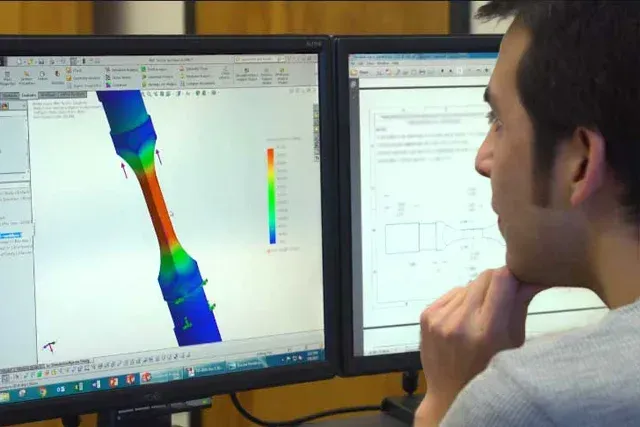 An FMI employee sitting at a computer developing a design of composite material.